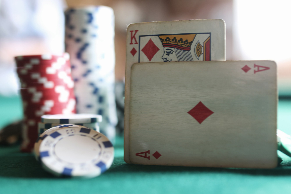 A little worn playing cards with chips next to them put on top of a green cloth table